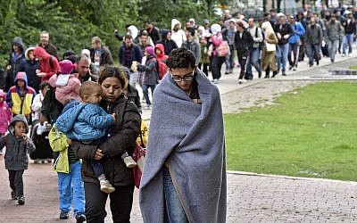 Migrants walk from the main station in Dortmund, Germany, to a hall where they get first attendance Sunday, Sept. 6, 2015. Thousands of migrants and refugees arrived in Dortmund by trains. (AP Photo/Martin Meissner)