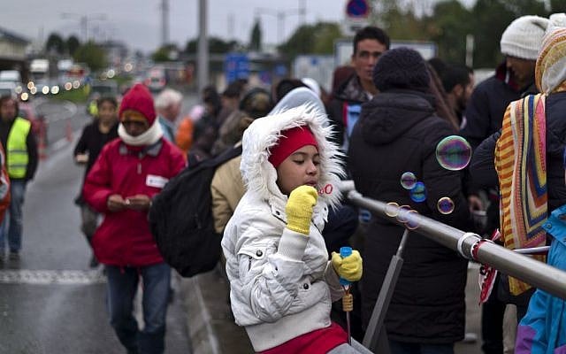 An Afghan refugee girl blows bubbles while waiting on a bridge after she and other migrants spent the night waiting for their registration and transport by German police to a refugee shelter in Freilassing, Germany, Thursday, Sept. 24, 2015. (AP Photo/Muhammed Muheisen)