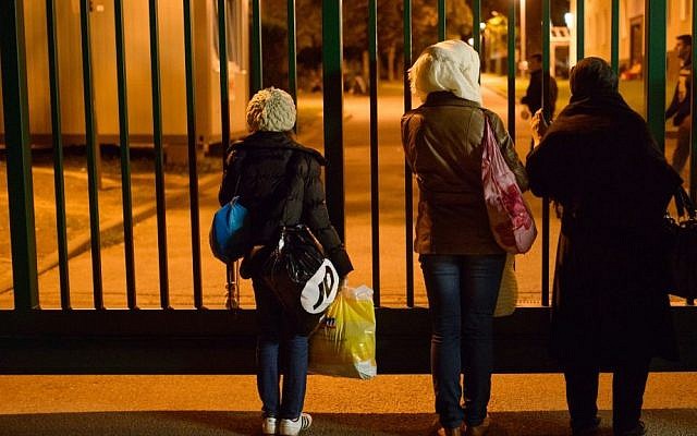 In this Sept. 16, 2015 photo Raghad and Reem Habashieh, from left, and their mother Khawla Kareem look into an asylum center they’d been assigned to in Chemnitz, eastern Germany. In the afternoon of the day before, the family _44-year-old Khawla Kareem, her daughters Reem, 19, and Raghad, 11, and sons Mohammed, 17, and Yaman, 15 _ finally got their papers, all stamped, with passport photos, a new address and train tickets to go to Chemnitz, a city of 240,000 near the Czech border. (AP Photo/Candy Welz)
