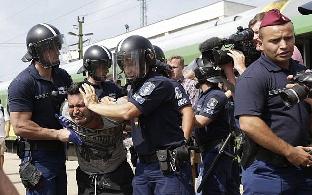 A migrant is detained after the train they were traveling in from Budapest arrived in Bicske, Hungary, Thursday, Sept. 3, 2015. (AP/Petr David Josek)