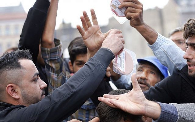 Asylum-seekers queue for a food donation out of a car coming over from Wuppertal, Germany, in front of Keleti railway station in Budapest, Hungary, Sept. 4, 2015. (AP/Frank Augstein)