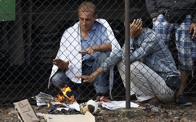Men burn papers to warm themselves outside a train that was stopped in Bicske, Hungary, Sept. 4, 2015. (AP/Petr David Josek)