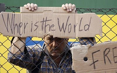 A man holds onto a fence outside a train that was stopped in Bicske, Hungary, Sept. 4, 2015. (AP/Petr David Josek)