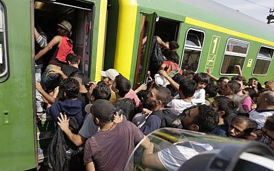 Migrants rush to board a train in Bicske, Hungary,  September 3, 2015. Over 150,000 migrants have reached Hungary this year, most via the southern border with Serbia. Many apply for asylum, but quickly try to leave for richer EU countries. (AP/Petr David Josek)