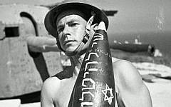 A Jewish Brigade soldier carries an artillery shell. The Hebrew inscription on the shell translates as "a gift to Hitler."