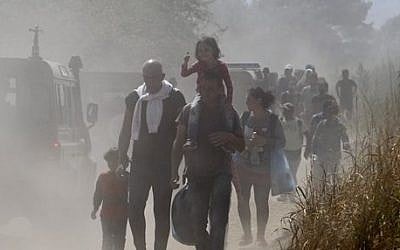 A group of migrants walk along a dusty road towards a transit center for migrants, after crossing the border from Greece to Macedonia, near the southern Macedonian town of Gevgelija, Monday, Aug. 31, 2015  (AP Photo/Boris Grdanoski)