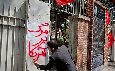 An Iranian student writes an anti-US slogan in Persian which reads: "Death to America" at the gate of the former US Embassy where an anti-US plaque was unveiled in a ceremony, in Tehran, Iran, Wednesday, Sept. 2, 2015 [Ebrahim Noroozi/AP]