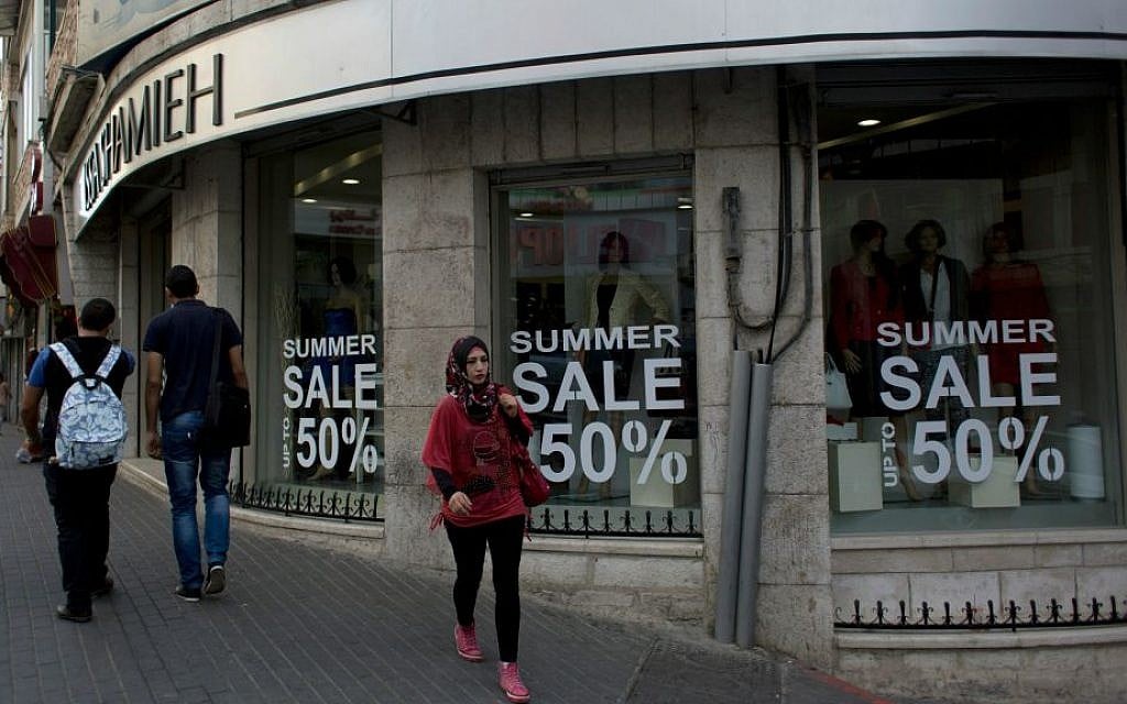 Palestinians walk past a boutique in the West Bank city of Ramallah, Tuesday, Sept. 29, 2015. (AP Photo/Nasser Nasser)