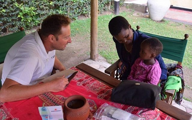 Dr Sagi Assa of Wolfson Medical Center examines 18-month-old Queenie as soon as the group arrived in Arusha. (Randi Weiss/SACH) Dr Sagi Assa of Wolfson Medical Center examined 18-month-old Queenie, sitting on her mother' lap, as soon as the group arrived in Arusha. (Randi Weiss/SACH)