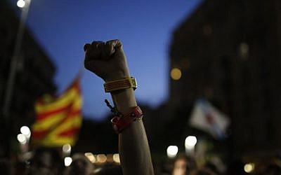 A Catalonian independence supporter wearing a bracelet with the "estelada" or pro-independence flag colors, raises her fist during reactions after the vote in Barcelona, Spain, Sunday September 27, 2015 (AP Photo/Emilio Morenatti)