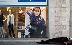 A homeless man sleeping in front of a department store in Jerusalem on December 4, 2014. (Danielle Shitrit/Flash90)