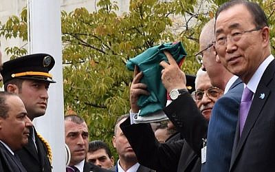 Palestinian Authority President Mahmoud Abbas raises the Palestinian flag as UN Secretary General Ban Ki-moon looks on during a ceremony in the rose garden of the UN's New York headquarters, September 30, 2015. (AFP PHOTO/TIMOTHY A. CLARY) 