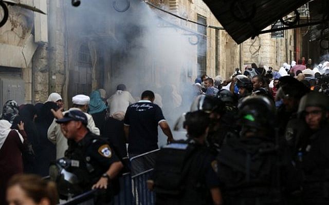 Security forces stand guard as Palestinians walk away from tear gas smoke during clashes between Palestinians and Israeli police at Al-Aqsa mosque compound in Jerusalem's Old City, September 13, 2015. (AFP/AHMAD GHARABLI)