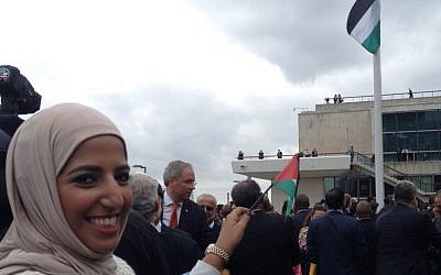 A woman smiles and waves a small Palestinian flag as the Palestinian banner is raised outside UN Headquarters in New York during the 70th Session of the UN General Assembly on September 30, 2015 (Raphael Ahren) 