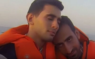 Ahmed (left) embraces a fellow passenger as thier boat arrives on the shores of the Greek island of Lesbos after the arduous journey across the Aegean sea. (Screenshot from YouTube)