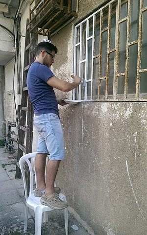A volunteer gives the window bars a fresh coat of paint on September 4. (Courtesy Eli Naiditch)