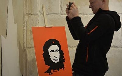 A visitor stands next to an artwork depicting Russian President Vladimir Putin as Argentine-born revolutionary Ernesto Che Guevara during the "Putin Universe" exhibition in Moscow on October 6, 2015. (Natalia Kolesnikova/AFP)