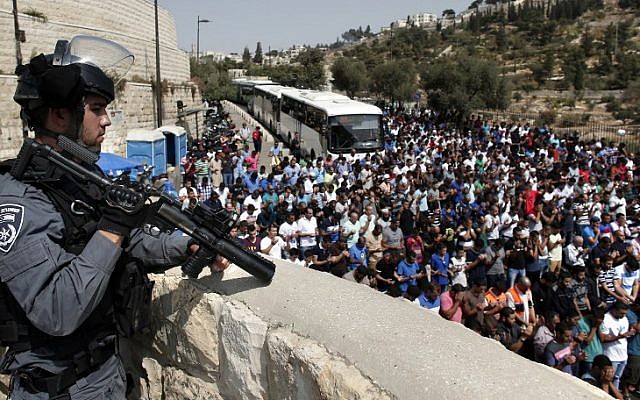 A policeman stands guard as Palestinian men, who were prevented from entering the Temple Mount compound to attend Friday prayers, pray at the Lions Gate of Jerusalem's Old City, October 2, 2015. (AFP/Thomas Coex) A policeman stands guard as Palestinian men, who were prevented from entering the Temple Mount compound to attend Friday prayers, pray at the Lions Gate of Jerusalem's Old City, October 2, 2015. (AFP/Thomas Coex)