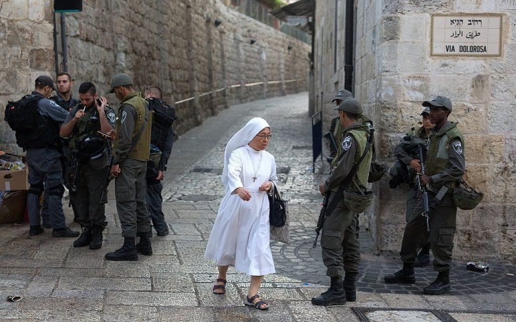 A nun walks past Israeli police as they stand guard in the Via Dolorosa street in the Old City of Jerusalem on October 4, 2015. (AFP/MENAHEM KAHANA) A nun walks past Israeli police as they stand guard in the Via Dolorosa street in the Old City of Jerusalem on October 4, 2015. (AFP/MENAHEM KAHANA)