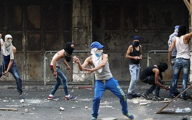 Illustrative. Palestinian youth throw stones towards Israeli security forces during clashes in the West Bank town of Hebron on October 4, 2015. (AFP/Hazem Bader) Illustrative. Palestinian youth throw stones towards Israeli security forces during clashes in the West Bank town of Hebron on October 4, 2015. (AFP/Hazem Bader)