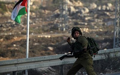 An Israeli soldier hurls a smoke grenade during clashes with Palestinian youth close to the Jewish settlement of Bet El, in the West Bank city of Ramallah on October 4, 2015. (AFP/ABBAS MOMANI)