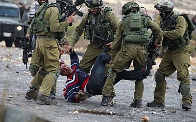 Israeli soldiers detain a Palestinian stone thrower near Beit El, on the outskirts of the West Bank city of Ramallah, on October 7, 2015. (AFP/ABBAS MOMANI) Israeli soldiers detain a Palestinian stone thrower near Beit El, on the outskirts of the West Bank city of Ramallah, on October 7, 2015. (AFP/ABBAS MOMANI)