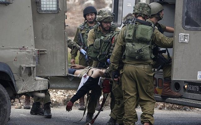 Israeli soldiers carry on a stretcher a wounded Palestinian stone thrower who was shot by infiltrated members of the Israeli security forces during clashes in Beit El, on the outskirts of the West Bank city of Ramallah, on October 7, 2015. (AFP/ABBAS MOMANI)