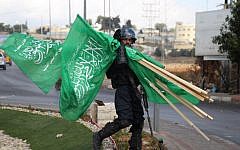 A member of Israeli security forces carries flags of the Hamas terror group that were seized during clashes with Palestinian protesters near the West Bank settlement of Beit El, on October 8, 2015. (AFP/Abbas Momani)