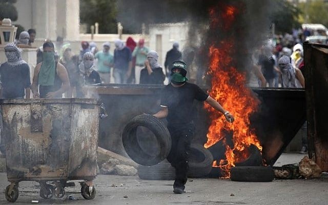 Illustrative photo of a Palestinian protester burning tires during clashes with Israeli security forces in the West Bank on October 10, 2015. (AFP/ABBAS MOMANI) Illustrative photo of a Palestinian protester burning tires during clashes with Israeli security forces in the West Bank on October 10, 2015. (AFP/ABBAS MOMANI)