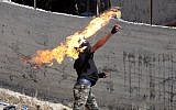 Illustrative: A Palestinian hurls a Molotov cocktail toward Israeli security forces during clashes, near the city of Hebron, in the West Bank, on October 11, 2015. (AFP/Hazem Bader)