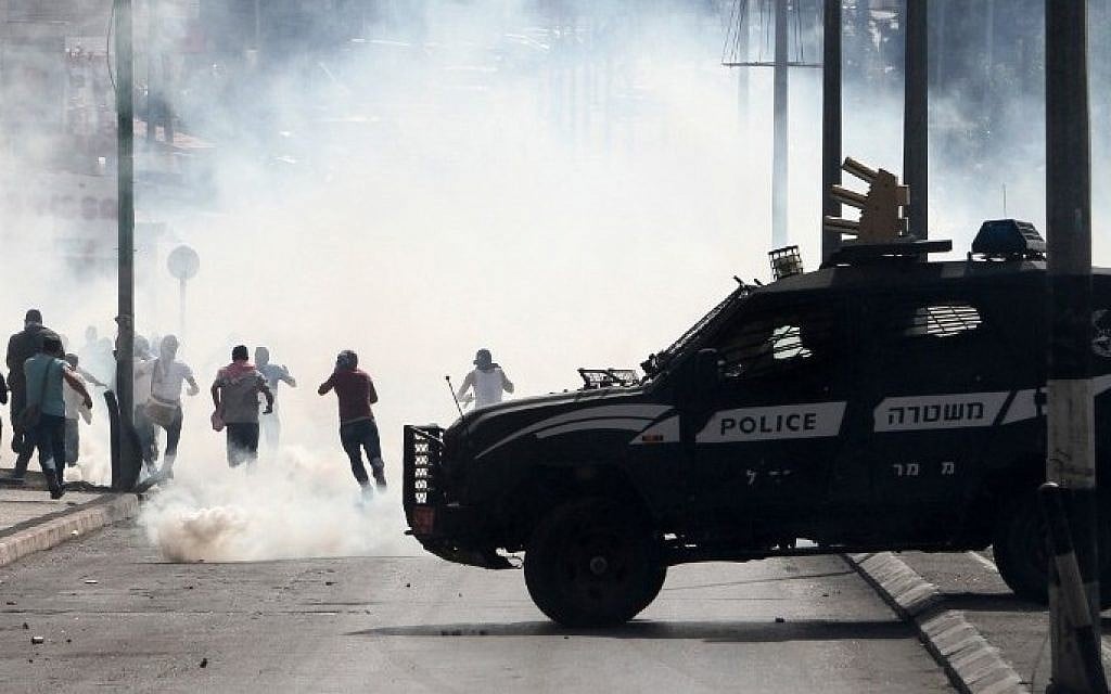 An Israeli police vehicle drives in front of Palestinian protesters running away during clashes on October 13, 2015 in the West Bank city of Bethlehem. (AFP/MUSA AL-SHAER)