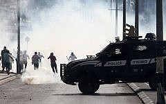 An Israeli police vehicle drives in front of Palestinian protesters running away during clashes on October 13, 2015 in the West Bank city of Bethlehem. (AFP/MUSA AL-SHAER)