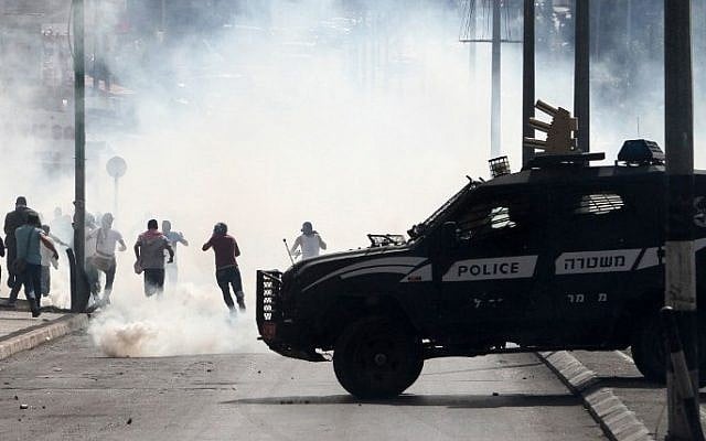 An Israeli police vehicle drives in front of Palestinian protesters running away during clashes on October 13, 2015 in the West Bank city of Bethlehem. (AFP/MUSA AL-SHAER) An Israeli police vehicle drives in front of Palestinian protesters running away during clashes on October 13, 2015 in the West Bank city of Bethlehem. (AFP/MUSA AL-SHAER)