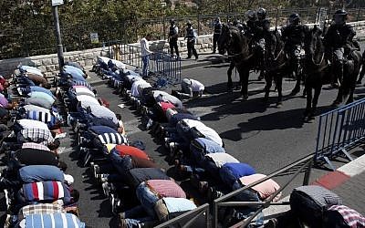 Israeli police stand guard as Palestinian Muslims pray on the streets of the Wadi al-Joz neighborhood in East Jerusalem during the Friday prayers following restrictions by Israeli police preventing Palestinians under 40 years old from entering the Temple Mount, on October 16, 2015. (AFP PHOTO / THOMAS COEX) Israeli police stand guard as Palestinian Muslims pray on the streets of the Wadi al-Joz neighborhood in East Jerusalem during the Friday prayers following restrictions by Israeli police preventing Palestinians under 40 years old from entering the Temple Mount, on October 16, 2015. (AFP PHOTO / THOMAS COEX)