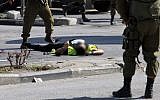 Israeli security forces stand next to the body of a Palestinian man disguised as a news photographer who carried out a stabbing attack against a soldier at the entrance to the city of Hebron on October 16, 2015 (Hazem Bader/AFP)