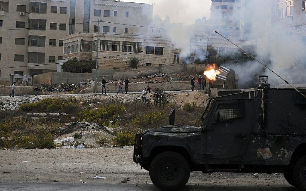 An Israeli armored vehicle fires tear gas at Palestinian protesters during clashes next to the Jewish settlement of Beit El, north of Ramallah on October 19, 2015. (AFP/ ABBAS MOMANI)
