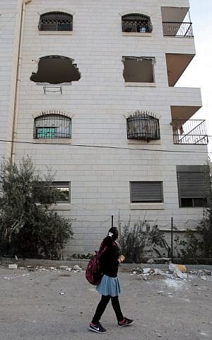 A Palestinian schoolgirl walks past a building housing the apartment of Maher al-Hashlamoun after its interior was destroyed by Israeli troops in the West Bank city of Hebron on October 20,2015. (AFP PHOTO/HAZEM BADER