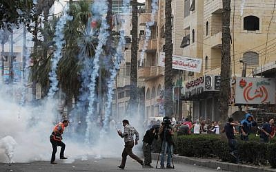 Palestinian stone throwers and journalists take cover from tear gas fired by Israeli security forces during clashes following Friday prayers on October 23, 2015, in the West Bank town of Hebron (Hazem Bader/AFP) Palestinian stone throwers and journalists take cover from tear gas fired by Israeli security forces during clashes following Friday prayers on October 23, 2015, in the West Bank town of Hebron (Hazem Bader/AFP)