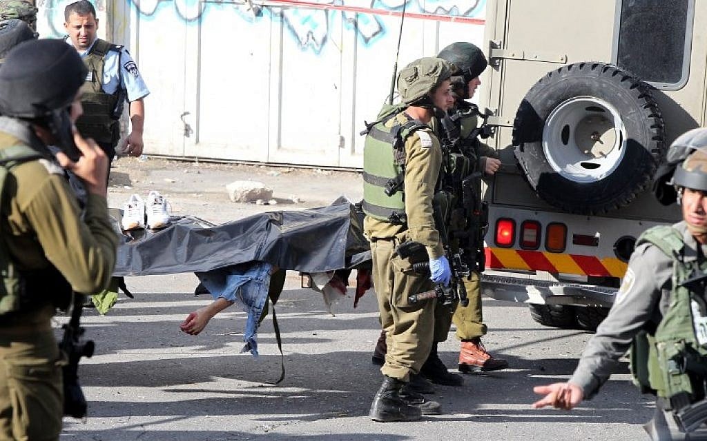 Israeli security forces carry the body of a Palestinian man who stabbed and wounded an IDF soldier before being shot dead by a Border Police officer in Hebron on October 29, 2015. (AFP/HAZEM BADER) Israeli security forces carry the body of a Palestinian man who stabbed and wounded an IDF soldier before being shot dead by a Border Police officer in Hebron on October 29, 2015. (AFP/HAZEM BADER)