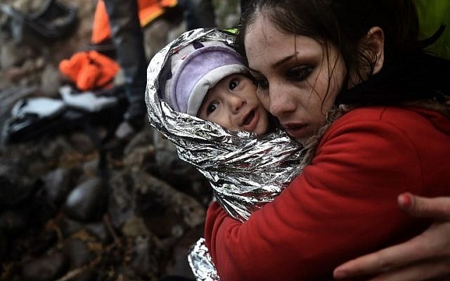 A woman hugs a baby wrapped in an emergency blanket as refugees and migrants arrive on the Greek island of Lesbos after crossing the Aegean sea from Turkey on October 1, 2015. (AFP PHOTO / ARIS MESSINIS)