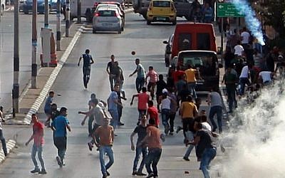Palestinian demonstrators run for cover from tear gas fired by Israeli security forces during clashes in the West Bank town of Bethlehem on October 2, 2015. (Musa al Shaer/AFP)