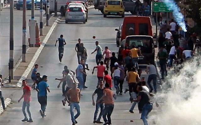 Palestinian demonstrators run for cover from tear gas fired by Israeli security forces during clashes in the West Bank town of Bethlehem on October 2, 2015. (Musa al Shaer/AFP)