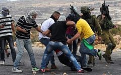 IDF soldiers and undercover security forces detain a Palestinian stone thrower during clashes in Beit El, on the outskirts of the West Bank city of Ramallah, on October 7, 2015. (AFP/ABBAS MOMANI)