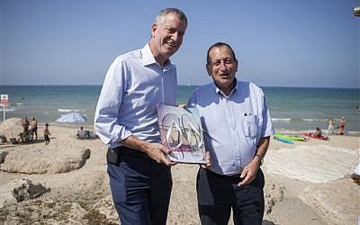 New York City Mayor Bill de Blasio, left, receives a gift from Tel Aviv counterpart Ron Huldai during their meeting in the coastal town on Saturday, Oct. 17, 2015. (AP Photo/Dan Balilty)