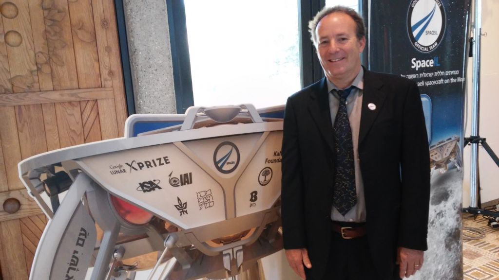 Curt Blake standing next to an actual-size artist rendition of the spacecraft (Simona Weinglass/Times of Israel)
