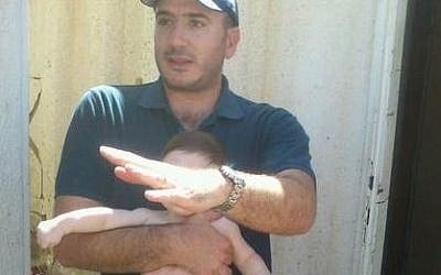 Moshe Marom, of Tekoa, holds his baby as he described a rock-throwing attack his family suffered while traveling home on Thursday, October 1, 2015. Marom's wife and another of his children were lightly wounded in the attack. (Courtesy Tekoa security)