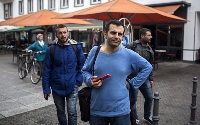 In this Sept. 16, 2015, photo, Osman al-Haj Osman, center, walks across a street in Saarlouis, Germany, with his friends Mohammed al-Haj, left, and Dr. Ahmed Naasan, who recently arrived from Aleppo, Syria. (Santi Palacios/AP) In this Sept. 16, 2015, photo, Osman al-Haj Osman, center, walks across a street in Saarlouis, Germany, with his friends Mohammed al-Haj, left, and Dr. Ahmed Naasan, who recently arrived from Aleppo, Syria. (Santi Palacios/AP)