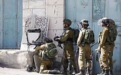 Illustrative: IDF soldiers stand with their weapons during clashes with Palestinian demonstrators in the West Bank city of Hebron, on Tuesday, October 13, 2015. (AP Photo/Nasser Shiyoukhi)