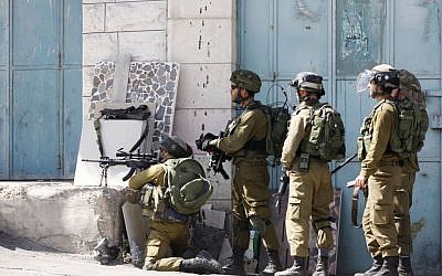 Illustrative: IDF soldiers stand with their weapons during clashes with Palestinian demonstrators in the West Bank city of Hebron, on Tuesday, October 13, 2015. (AP Photo/Nasser Shiyoukhi)