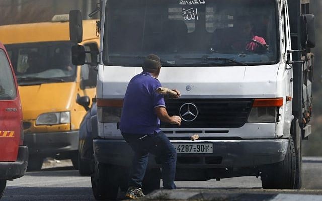 Avraham Hasano swings a large stick at an approaching truck driven by a Palestinian man at Fawar junction near the West Bank city of Hebron on Tuesday, October 20, 2015. Hasano had gotten out from his car after it was it by Palestinian ston throwers, He was run over by the truck and later died (AP Photo/Nasser Shiyoukhi)